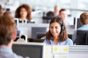 Young woman working in call center, surrounded by colleagues